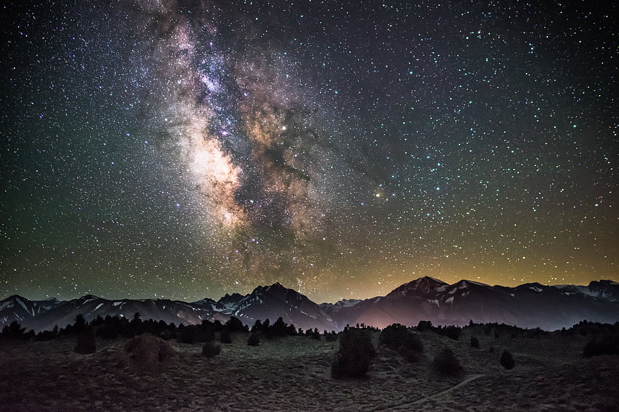 Milky Way Galaxy Arching Over Snow-Capped Mountain Ranges Under a Star-Filled Night Sky HD wallpaper