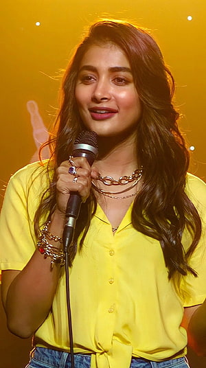 Pooja Hegde Performing on Stage in a Bright Yellow Shirt with Microphone HD phone wallpaper