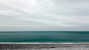 Minimalist Ocean Horizon with Calm Teal Waters and Gravel Shoreline HD wallpaper