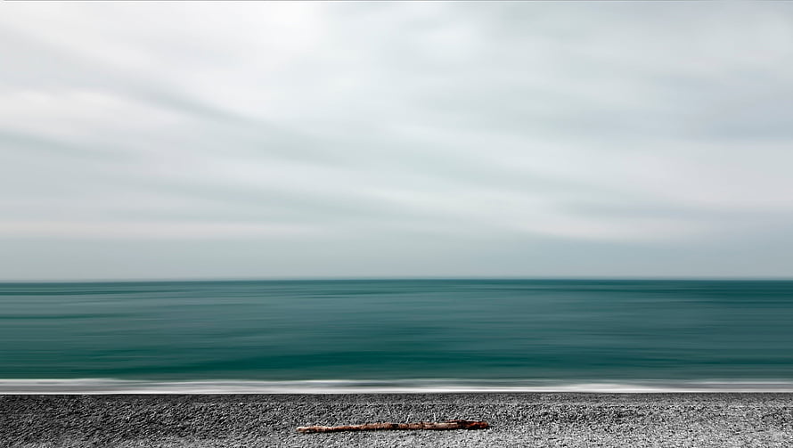 Minimalist Ocean Horizon with Calm Teal Waters and Gravel Shoreline HD wallpaper