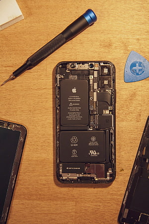 Disassembled Apple iPhone Internal Components and Repair Tools on Wooden Workbench HD phone wallpaper