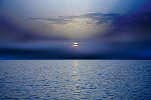 Serene Ocean Sunset with Sun Reflecting on Calm Water and Dark Clouds HD wallpaper