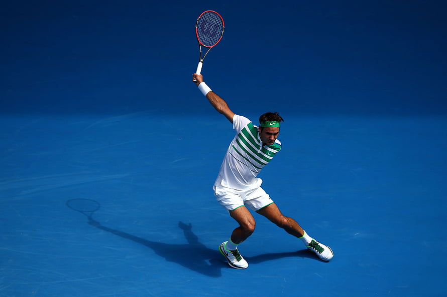 Roger Federer serving on a blue hard court in a white and green striped outfit HD wallpaper