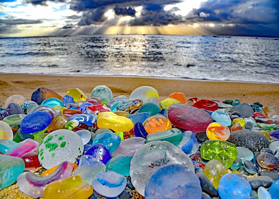 Colorful Sea Glass Collection on a Sandy Beach with Dramatic Ocean Sky HD wallpaper