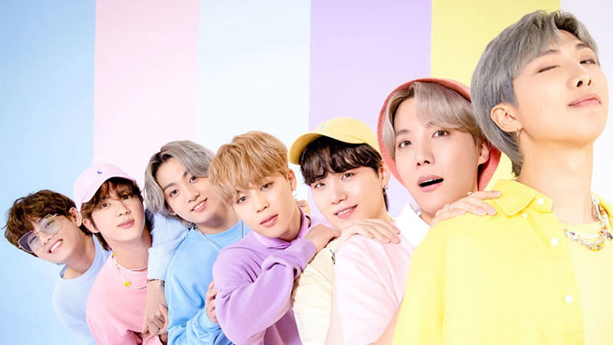 BTS Group Portrait in Pastel Colors with Playful Expressions and Casual Outfits HD wallpaper
