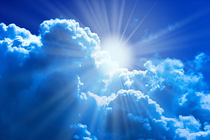 Bright Sunburst Breaking Through Fluffy Cumulus Clouds in a Deep Blue Sky HD wallpaper