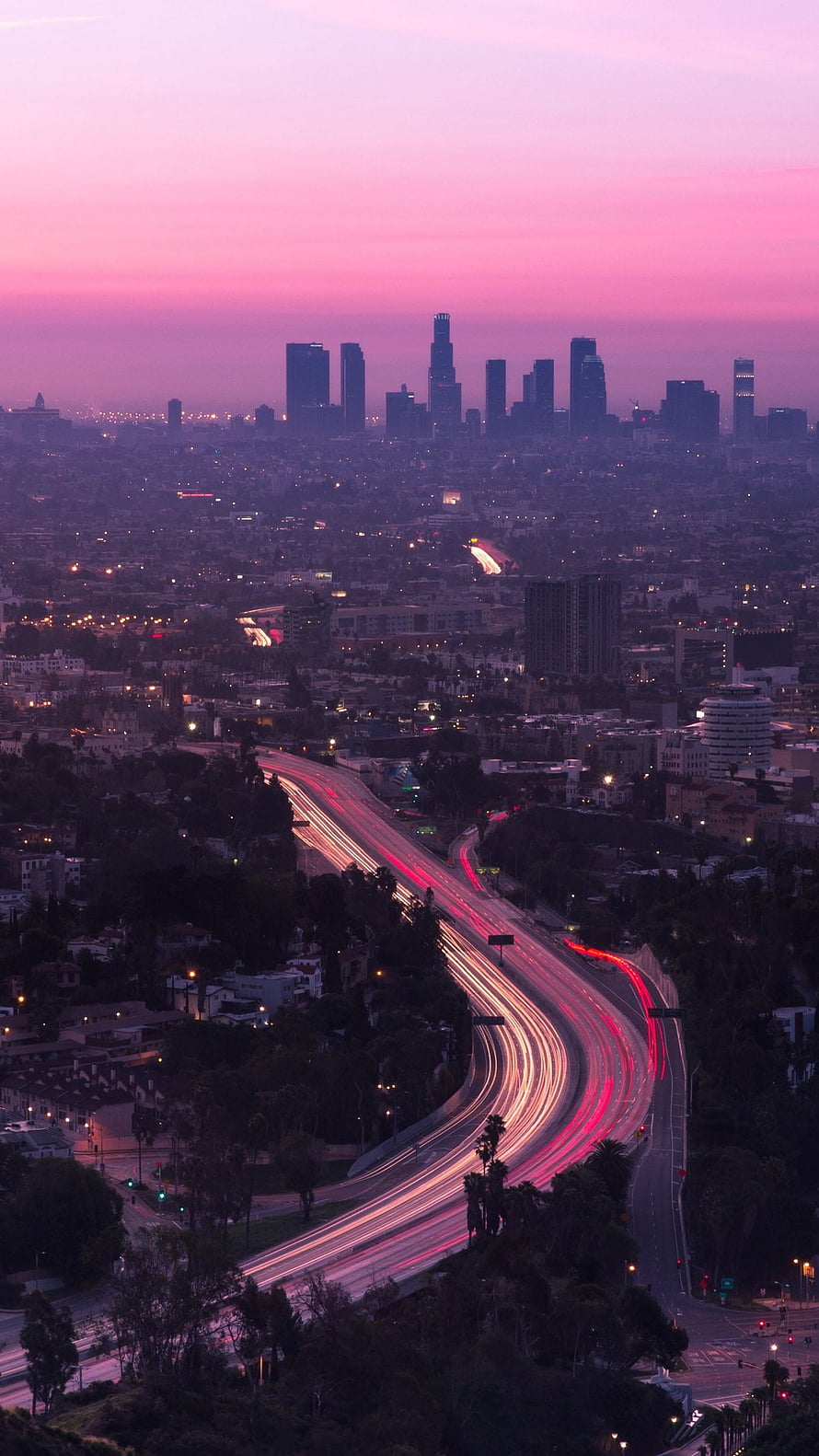 Los Angeles skyline at dusk with long exposure highway light trails and pink sunset sky HD phone wallpaper