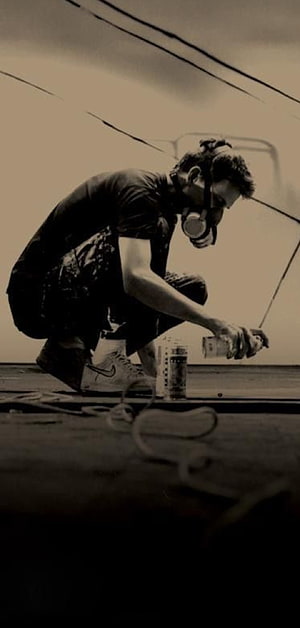 Street Artist Crouching with Spray Paint Can and Respirator Mask in Sepia Tone HD phone wallpaper