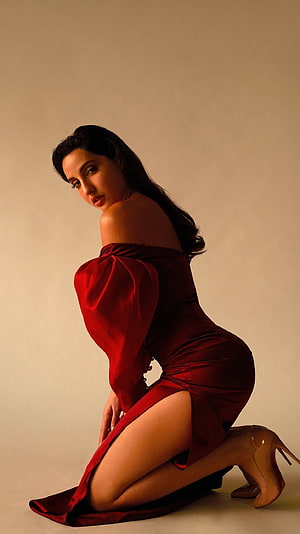 Nora Fatehi in a striking red off-shoulder gown with dramatic studio lighting HD phone wallpaper