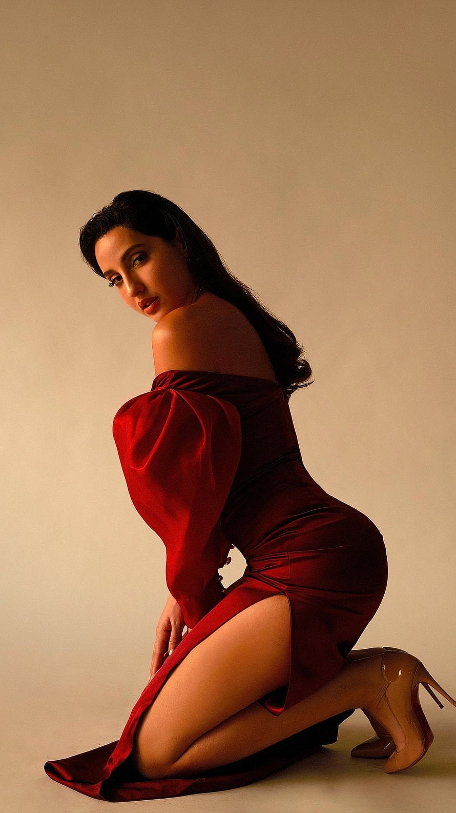 Nora Fatehi in a striking red off-shoulder gown with dramatic studio lighting HD phone wallpaper