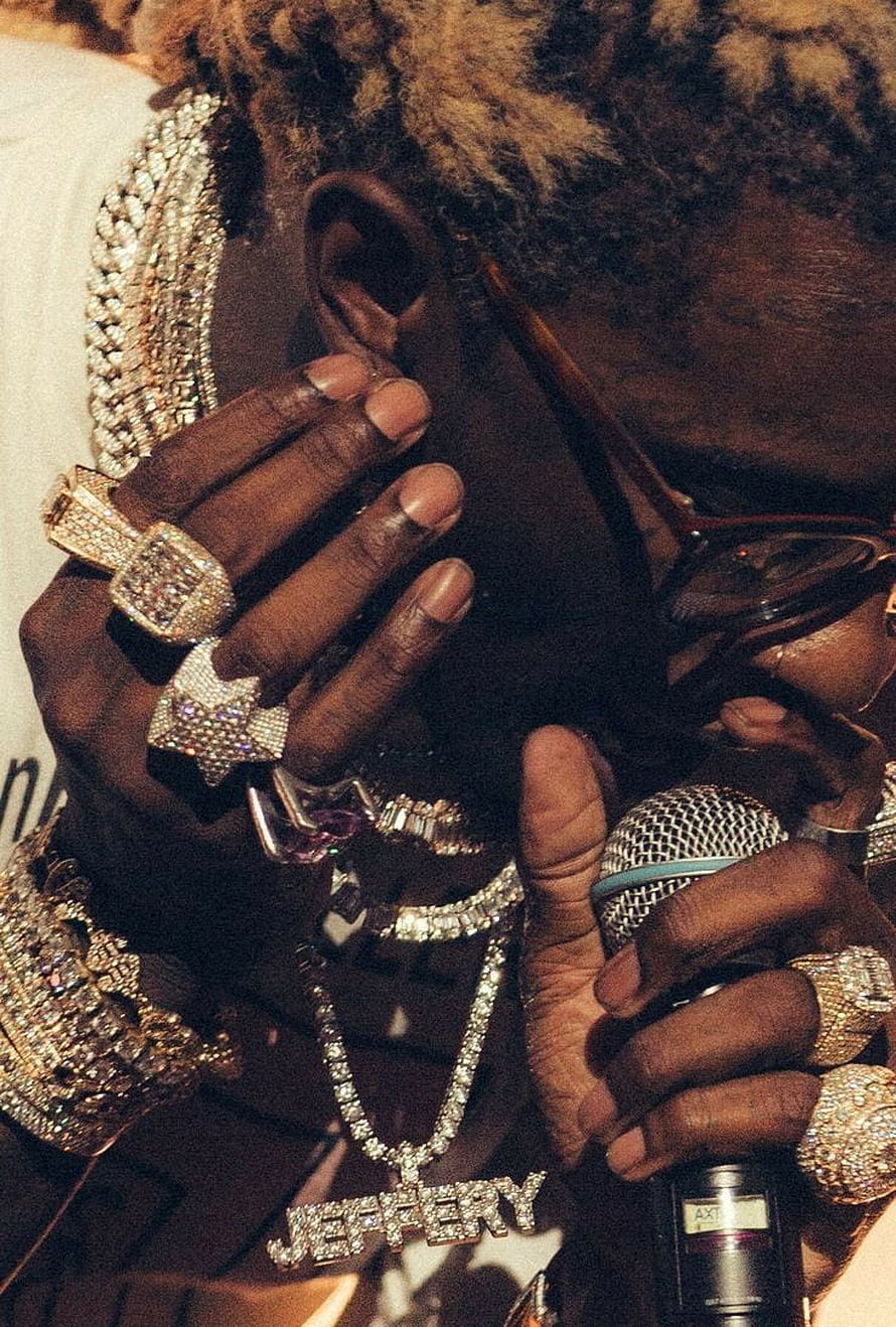 Young Thug performing on stage wearing diamond jewelry and holding a microphone HD phone wallpaper