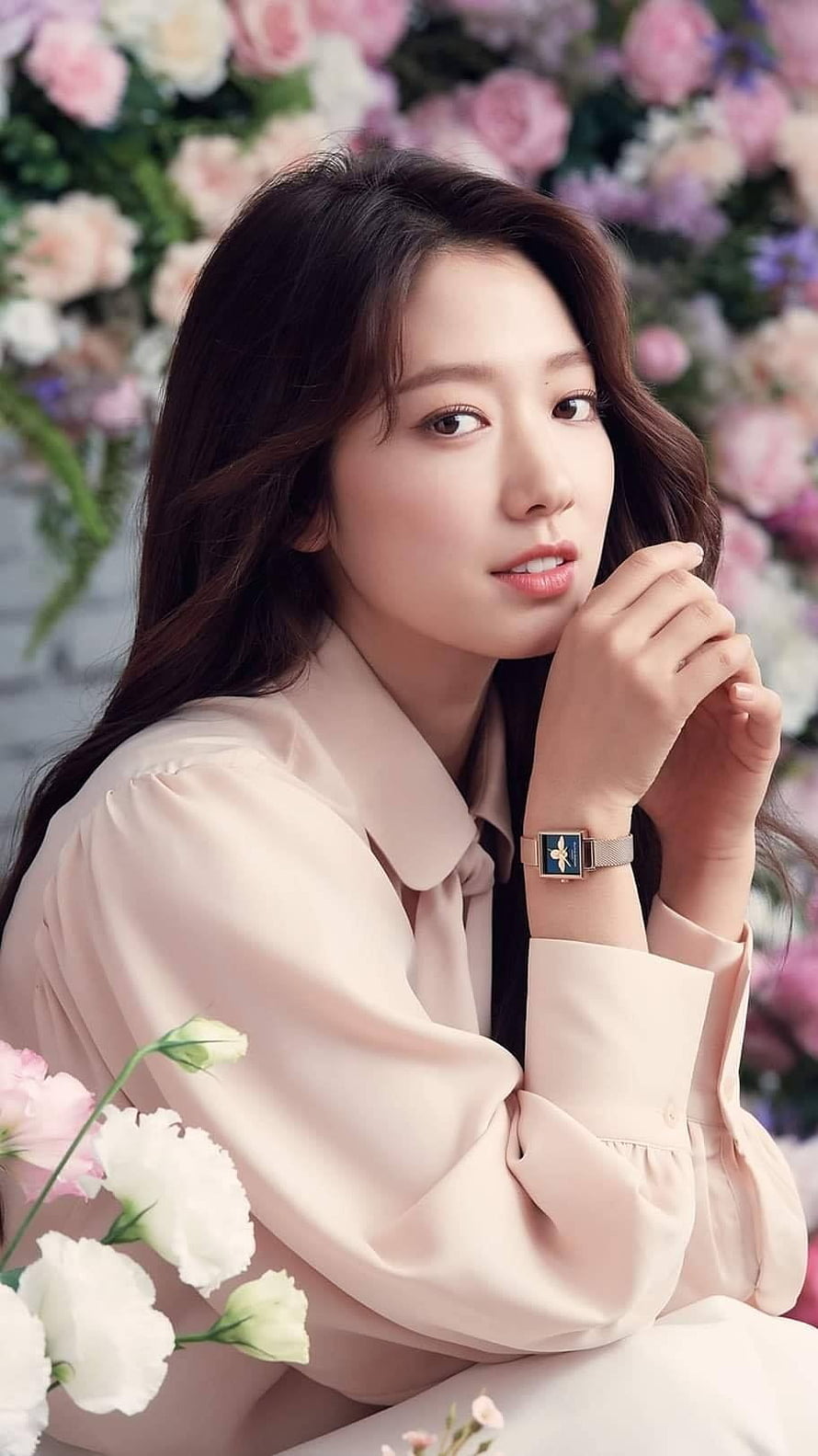 Park Shin Hye in a soft pink blouse posing with a floral wall backdrop and elegant wristwatch HD phone wallpaper