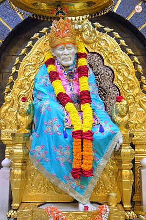 Shirdi Sai Baba Temple Idol Adorned in Turquoise Silk and Marigold Garlands HD phone wallpaper