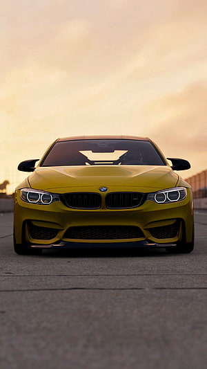 Front View of a Yellow BMW M4 GTS on a Track at Sunset HD phone wallpaper