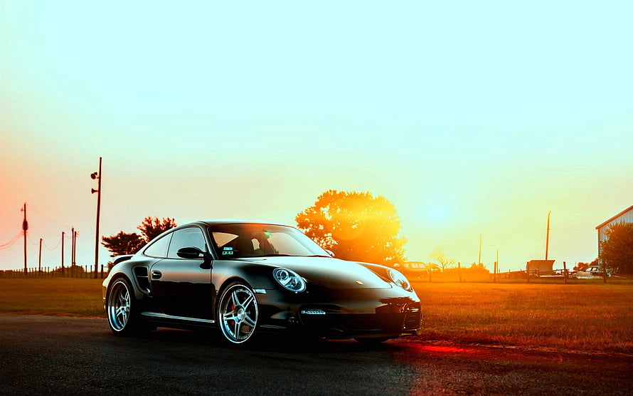 Black Porsche 911 Turbo S parked on a rural road at golden hour with warm sunset glow HD wallpaper