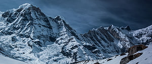 Dramatic Snow-Capped Alpine Peaks Under a Dark Stormy Sky HD wallpaper