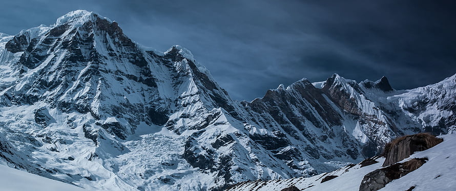 Dramatic Snow-Capped Alpine Peaks Under a Dark Stormy Sky HD wallpaper