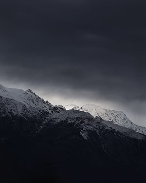 Moody Snow-Capped Mountain Peaks Under a Heavy Stormy Sky HD phone wallpaper
