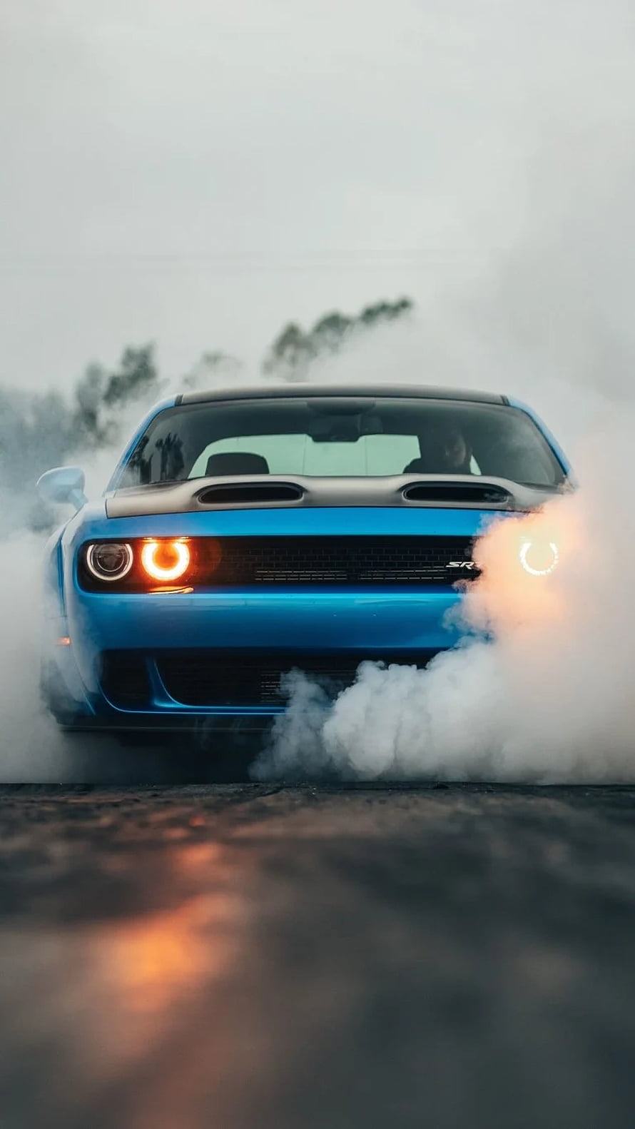 Blue Dodge Charger SRT performing a burnout with thick tire smoke on a foggy asphalt road HD phone wallpaper