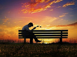 Silhouette of a man sitting alone on a park bench at sunset HD wallpaper