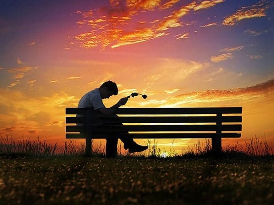 Silhouette of a man sitting alone on a park bench at sunset HD wallpaper