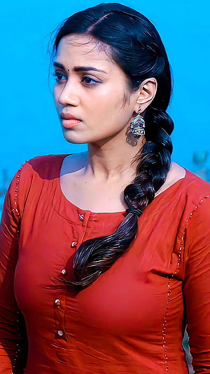 Nivetha Thomas in a red blouse with a long braid and traditional earrings HD phone wallpaper