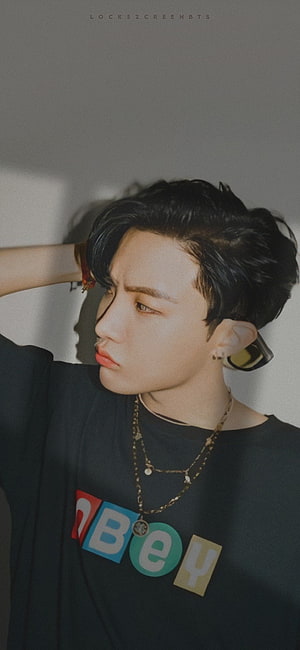 J-Hope from BTS in a black graphic tee with layered gold chains and a contemplative side profile HD phone wallpaper