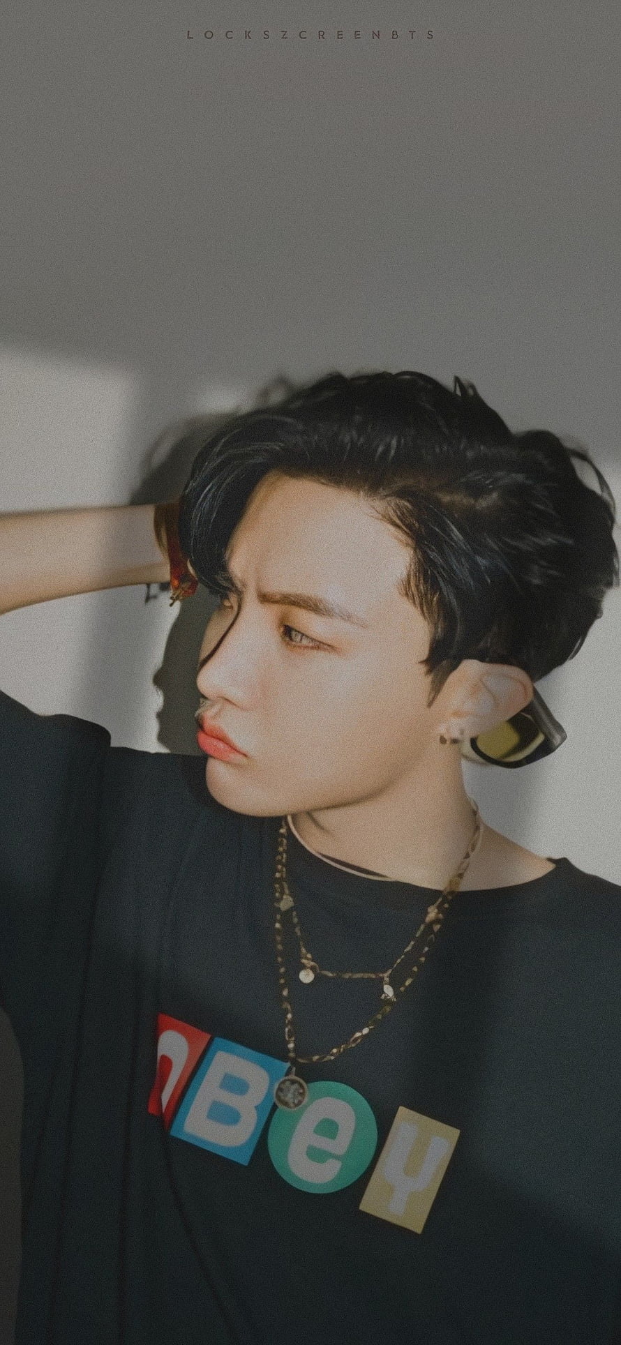 J-Hope from BTS in a black graphic tee with layered gold chains and a contemplative side profile HD phone wallpaper