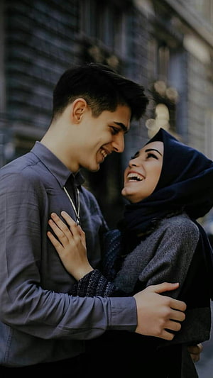 Smiling Muslim couple embracing affectionately in an urban setting HD phone wallpaper