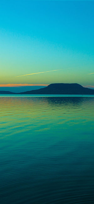 Tranquil Coastal Horizon at Dusk with Distant Island Silhouette and Calm Turquoise Waters HD phone wallpaper