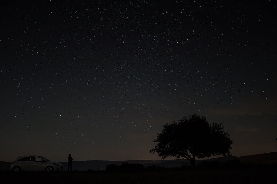 Starry Night Sky Over Silhouetted Tree, Car, and Person in Dark Rural Landscape HD wallpaper