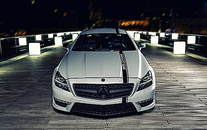 White Mercedes-Benz CLS with Black Racing Stripes Parked on a Nighttime Wooden Deck HD wallpaper