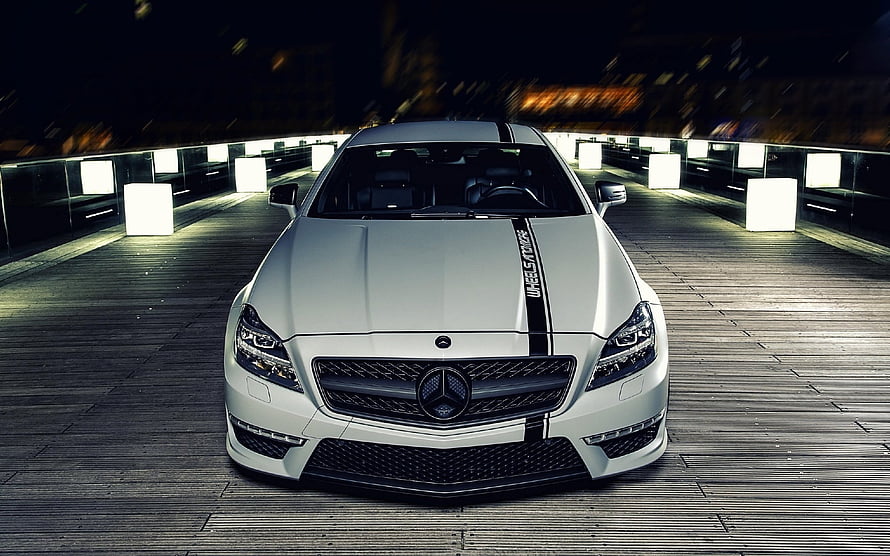 White Mercedes-Benz CLS with Black Racing Stripes Parked on a Nighttime Wooden Deck HD wallpaper