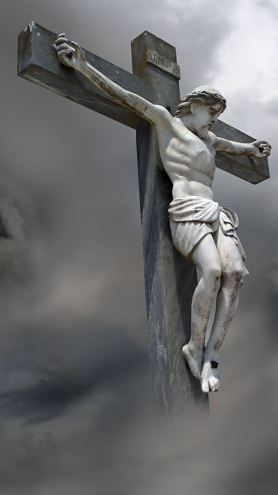 Weathered Stone Statue of Jesus Christ on the Cross Against a Dramatic Cloudy Sky HD phone wallpaper