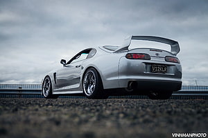 Silver Toyota Supra Mk4 Rear Three-Quarter View on Gravel Track Under Overcast Sky HD wallpaper