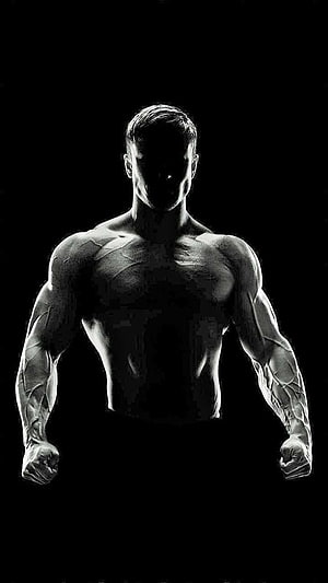Black and White Silhouette of a Muscular Bodybuilder Flexing in the Dark HD phone wallpaper