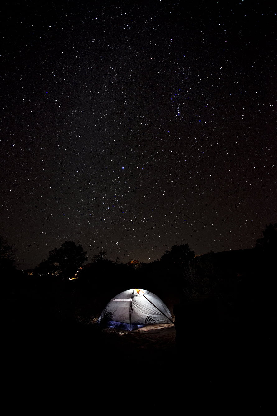 Illuminated Camping Tent Under a Vast Starry Night Sky in the Wilderness HD phone wallpaper