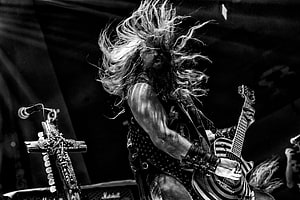 Zakk Wylde performing live on stage with long flowing hair and electric guitar in black and white HD wallpaper