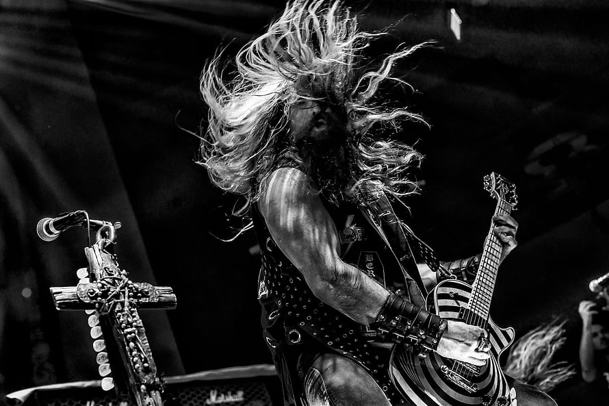 Zakk Wylde performing live on stage with long flowing hair and electric guitar in black and white HD wallpaper