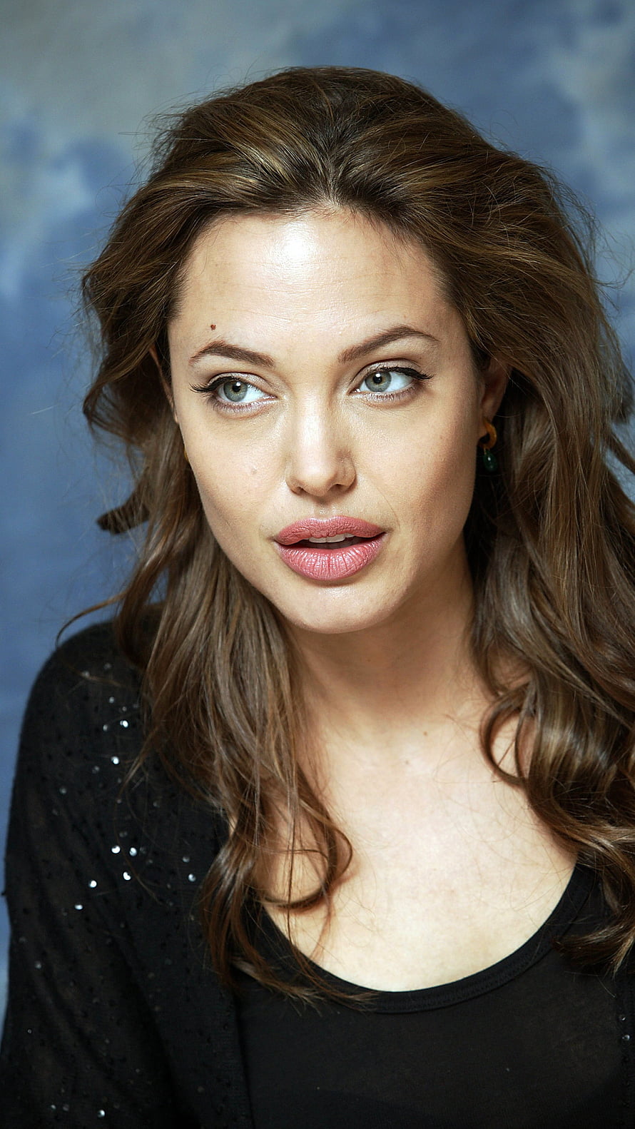 Angelina Jolie Portrait with Wavy Brown Hair and Black Top Against Blue Background HD phone wallpaper