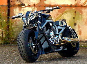 Custom Black and Silver Cruiser Motorcycle with Wide Tires Parked Against Rusty Wall HD wallpaper