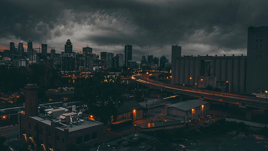 Montreal skyline at dusk with dramatic storm clouds and illuminated highway traffic HD wallpaper