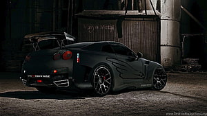 Matte Black Nissan GT-R R35 Widebody with Vortex Wing in Industrial Setting HD wallpaper