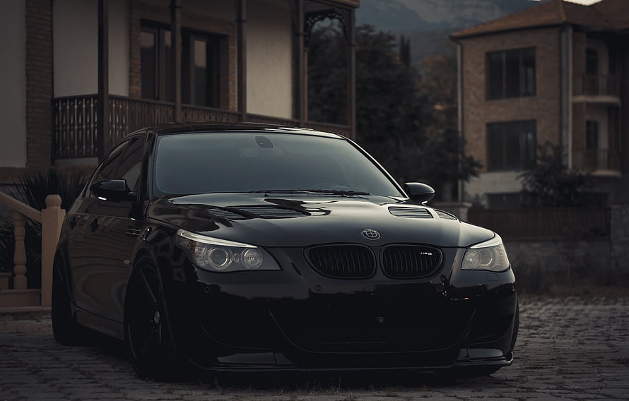 Black BMW E60 M5 Sedan Parked on Cobblestone Driveway at Dusk HD wallpaper