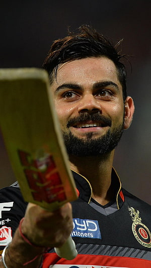 Virat Kohli smiling while holding a cricket bat in a Royal Challengers Bangalore jersey HD phone wallpaper