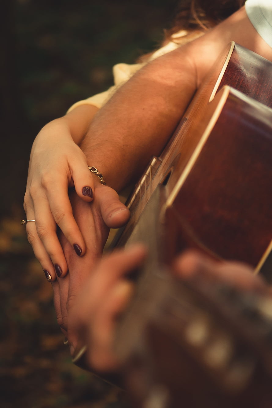 Intimate Close-Up of Two People Holding Hands While Playing Acoustic Guitar HD phone wallpaper