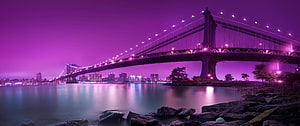Purple Tinted Night View of a Suspension Bridge Over Calm Water with City Skyline HD wallpaper