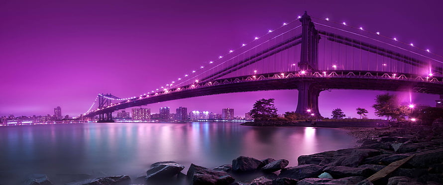 Purple Tinted Night View of a Suspension Bridge Over Calm Water with City Skyline HD wallpaper