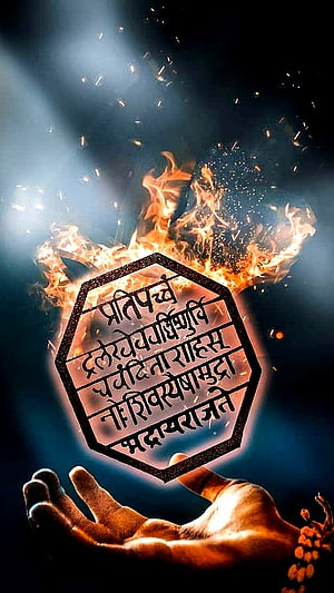 Flaming Octagonal Seal with Sanskrit Mantra Held in Open Palm Against Dark Background HD phone wallpaper