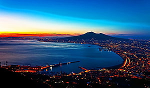 Naples Bay and Mount Vesuvius at Dusk with City Lights and Vibrant Sunset Sky HD wallpaper